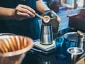 Barista`s hand putting ground coffee in stainless steel coffee grinder Royalty Free Stock Photo