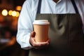 Barista serves a takeaway paper cup of steaming coffee gracefully