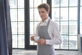 A barista smiling at the camera and holding a coffee drink for a customer. A positive male waiter looks at a cup of Royalty Free Stock Photo