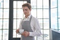 A barista smiling at the camera and holding a coffee drink for a customer. A positive male waiter looks at a cup of Royalty Free Stock Photo