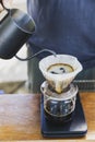 Barista spills hot water prepare filtered coffee from stainless steel teapot to drip paper maker on black simple weights.