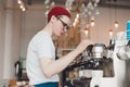 Barista stands behind the coffee machine and makes coffee