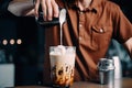 barista, stirring creamy mix of cold brew coffee and milk for iced latte