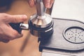 Barista tampering coffee in portafilter using tamper. Close-up fresh coffee preparation process Royalty Free Stock Photo