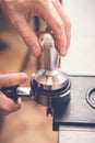 Barista tampering coffee in portafilter using tamper. Close-up fresh coffee preparation process Royalty Free Stock Photo