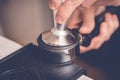 Barista tampering coffee in portafilter using tamper. Close-up fresh coffee preparation process Royalty Free Stock Photo