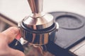 Barista tampering coffee in portafilter using tamper. Close-up fresh coffee preparation process Royalty Free Stock Photo