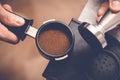 Barista tampering coffee in portafilter using tamper. Close-up fresh coffee preparation process Royalty Free Stock Photo