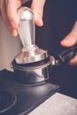Barista tampering coffee in portafilter using tamper. Close-up fresh coffee preparation process Royalty Free Stock Photo