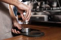 Barista tamping milled coffee in portafilter at bar counter, closeup Royalty Free Stock Photo