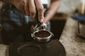 Barista using a tamper to press ground coffee into a portafilter. Coffee maker concept Royalty Free Stock Photo