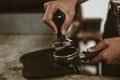 Barista using a tamper to press ground coffee into a portafilter. Coffee maker concept Royalty Free Stock Photo