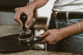 Barista using a tamper to press ground coffee into a portafilter. Coffee maker concept Royalty Free Stock Photo