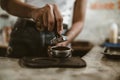 Barista using a tamper to press ground coffee into a portafilter. Coffee maker concept Royalty Free Stock Photo