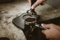 Barista using a tamper to press ground coffee into a portafilter. Coffee maker concept Royalty Free Stock Photo