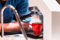 Barista waiting for coffee machine making an Espresso shot pouring out into the small red cup Royalty Free Stock Photo