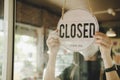 Barista, waitress woman wearing protection face mask turning close sign board on glass door in modern cafe coffee shop Royalty Free Stock Photo