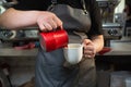 Barista woman prepares coffee with milk in a cafe. Female hands pour milk into a cup with coffee prepares latte. The Royalty Free Stock Photo