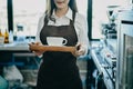 Barista woman serving coffee cup at cafe, Asian female barista holding coffee served . Royalty Free Stock Photo