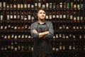 Barkeeper stands in wine cellar with shelves full of bottles Royalty Free Stock Photo