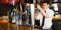 Barkeeper holding glass in front of beer dispenser