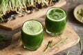 Barley grass juice in two glasses, with fresh blades growing in the background Royalty Free Stock Photo