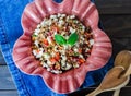 Barley salad with pomegranate, feta and mint on a pink ceramic and denin napkin