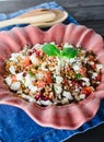 Barley salad with pomegranate, feta and mint on a pink ceramic and denin napkin