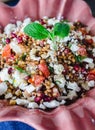 Barley salad with pomegranate, feta and mint on a pink ceramic and denin napkin