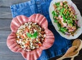 Barley salad with pomegranate, feta and mint on a pink ceramic and denin napkin