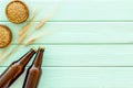 Barley or wheat as beer ingredient near beer bottles on green wooden background top view copy space