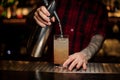 Barman adding soda water to an alcoholic orange cocktail