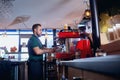 The barman, barista, makes a hot coffee drink at bar counter in