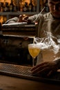 Barman carefully pouring steaming drink from shaker cup into wine glass