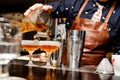 Barman completes the preparation of two alcoholic cocktails using bar equipment Royalty Free Stock Photo