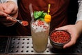 Barman is decorating cocktail with pink pepper Royalty Free Stock Photo