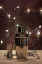 Barman equipment for making a cocktail on the background of wooden boards with natural blur of the garland.