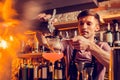 Barman feeling busy while pouring juice through sieve into glass