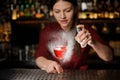 Barman girl decorating a glass of alcoholic cocktail with sparay