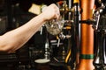 Barman going to pour beer into glass goblet from tap