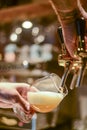 Barman hand at beer tap pouring a lager beer in a glass serving in a restaurant or pub.