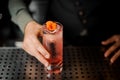 Barman hand holding a glass with summer light sour cocktail with pink peach liquor decorated with flower Royalty Free Stock Photo