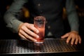 Barman hand holding a glass with summer light sour cocktail with pink peach liquor Royalty Free Stock Photo