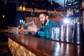 Barman with a hipster beard looks at laptop behind counter in