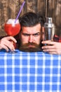 Barman or hipster holds cocktail with ice and straw.