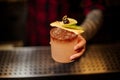 Barman holding a cocktail glass filled with tasty sweet alcoholic drink with ice and fruit slices Royalty Free Stock Photo