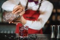 Barman holding a long spoon and glass filled with ice cubes on the bar counter Royalty Free Stock Photo