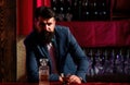 Barman luxury beverage concept. Man with beard holds glass with alcohol in bar. Waiter bartender in vintage vest with Royalty Free Stock Photo