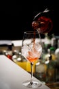 The barman making Aperol Spritz cocktail pours champagne into the glass with ice