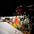 The barman making Aperol Spritz cocktail pours champagne into the glass with ice